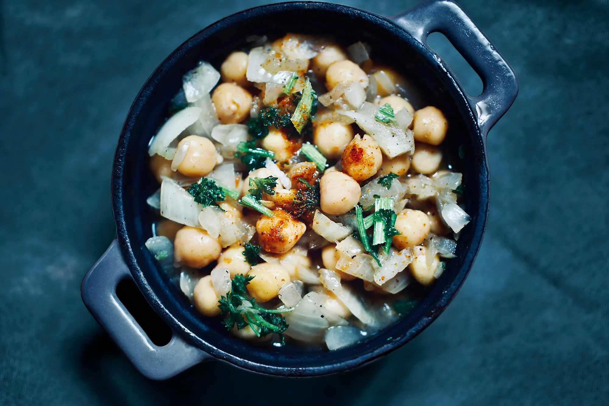 Chickpeas with onion and greens in a dark pot