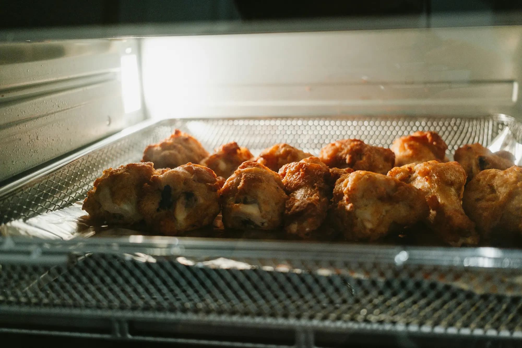 Golden pieces of food browning on a wire mesh tray
